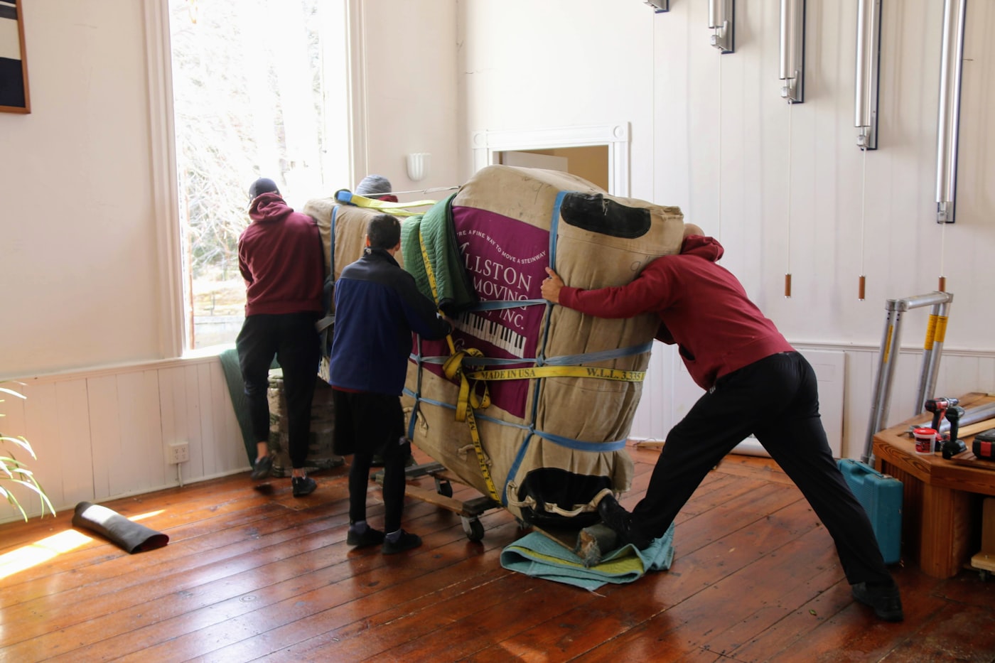Xu's Moving crew carefully moving a padded, wrapped item